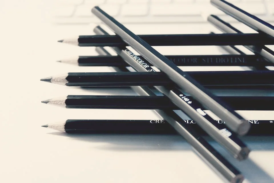 Black pencils lined up on a light surface